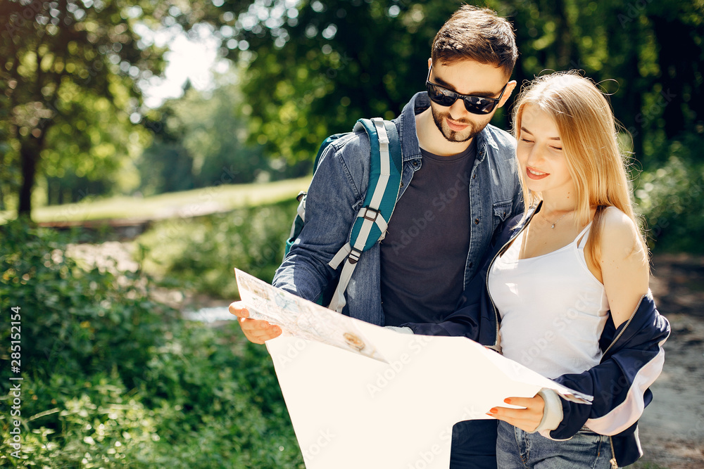 Naklejka premium Tourists in a summer forest. Couple with a map.