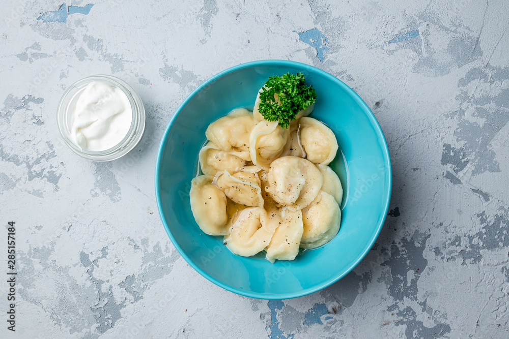 Dumplings with sour cream and herbs on grey concrete table Dumplings with sour cream and herbs on grey concrete table