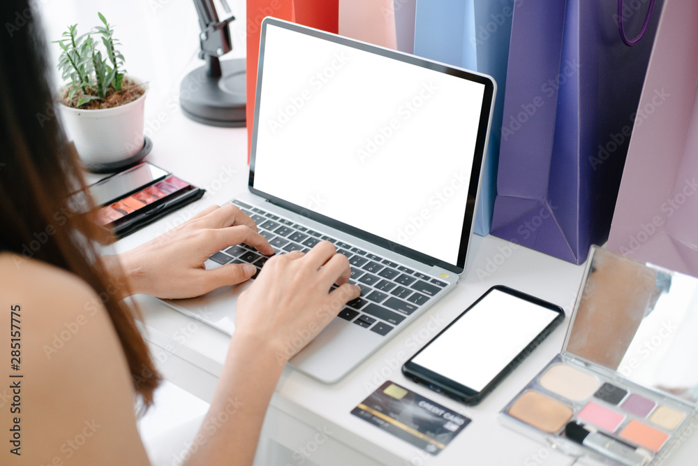 Fototapeta premium Mockup image of Beautiful woman shopping online with laptop and smartphone on online websites, mockup concept