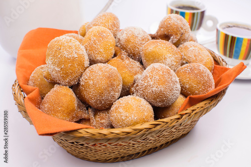 Traditional Brazilian mini fried cakes called bolinho de chuva in a basket in white breakfast table background