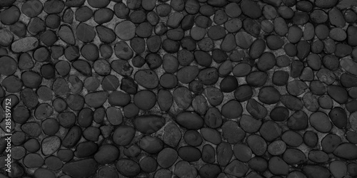 Panorama black pebbles texture background. Panoramic round dark black pebbles or gravel texture surface © phanasitti