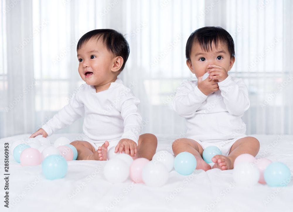 cheerful twin babies playing color ball on bed cheerful twin babies playing color ball on bed