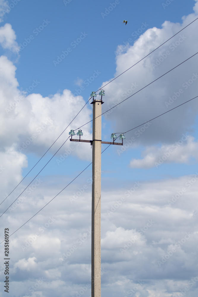 Concrete electric pole with wires in a green field against a blue sky. Concrete electric pole with wires in a green field against a blue sky.