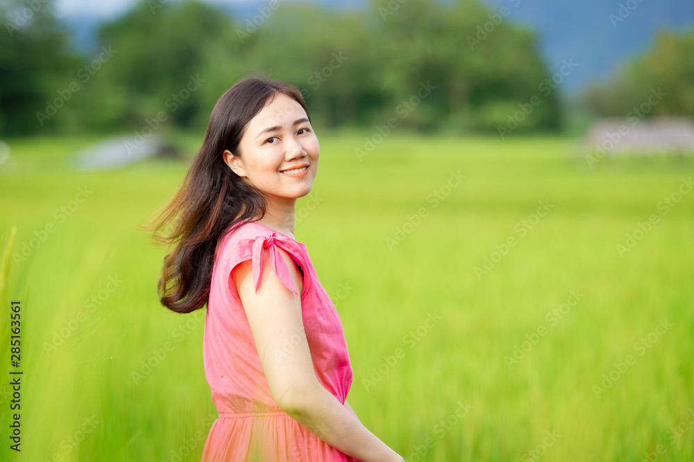Young Asian woman enjoying in the rice field. Portrait of beautiful Asian girl in the meadow close up. Concept of good living, healthy life style and wellness. Young Asian woman enjoying in the rice field. Portrait of beautiful Asian girl in the meadow close up. Concept of good living, healthy life style and wellness.