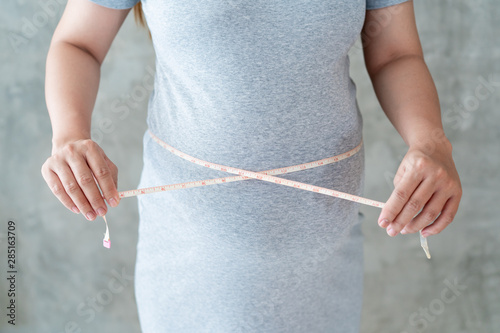 Huge belly of pregnant woman, the pregnant woman using meansuring tape to meansure her belly close up.  Concept of good healthy mom. photo