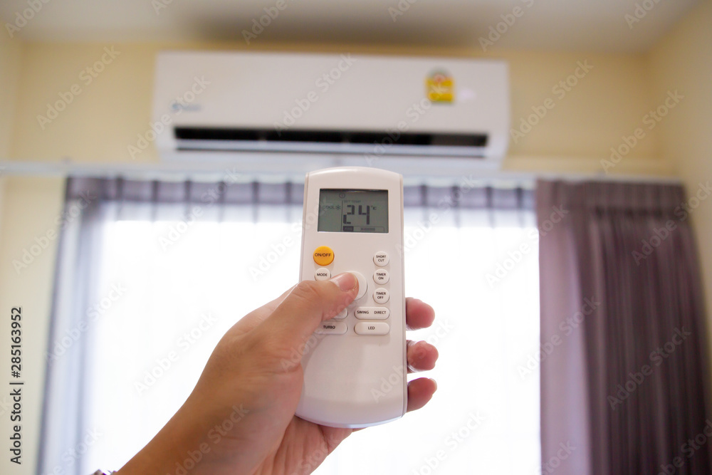 Man adusting the temperature of air conditioner by using a remote control. Man adusting the temperature of air conditioner by using a remote control.