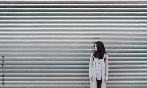 Wallpaper Mural A young European girl in a gray cardigan stands against a metal textured wall. Casual clothes. Copy space. Torontodigital.ca