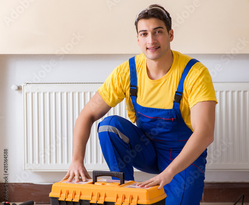 Young repairman contractor repairing heating panel