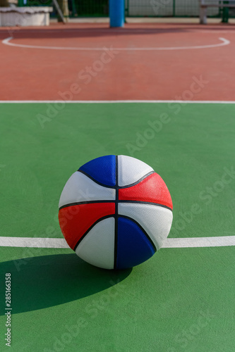 colorful basketball ball on top of the shooting area of an outdoor court