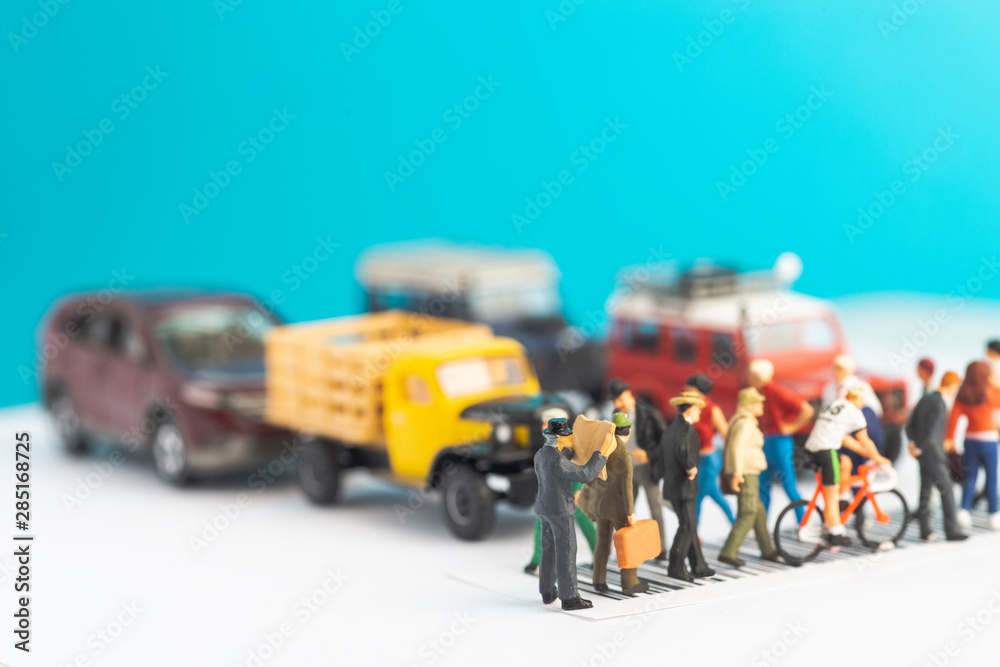 Fototapeta premium Miniature toys of a man reading newspaper, oblivious of his surrounding while crossing a street, reading habit concept.