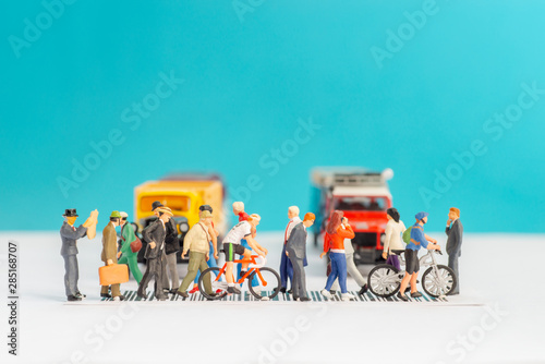 Miniature toys of crowd walking on zebra crossing with vehicles stopped concept.