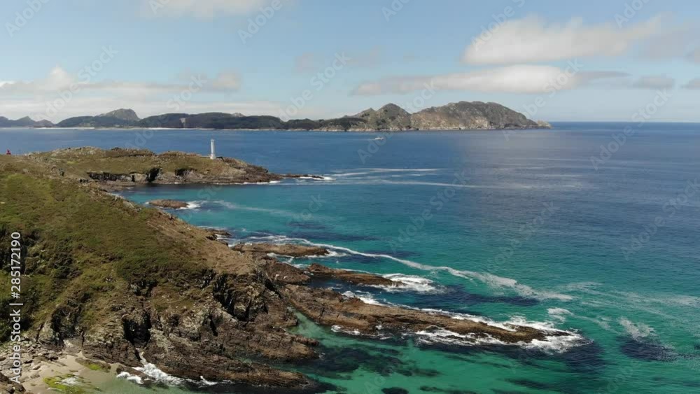 Beautiful aerial footage of Cies Islands from Costa da Vela on a sunny morning after the fog lifted. A fishing boat sails at the distance. Transparent greenish water at the foot of the cliffs.