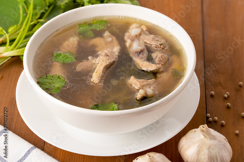 Top view of pork bone soup in white bowl on wooden table.