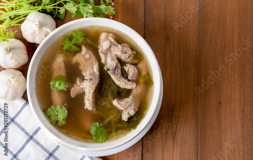 Top view of pork bone soup in white bowl on wooden table.