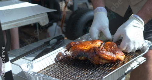 BBQ Chicken being taken off of a rack and placed on a table for slicing. 4k photo