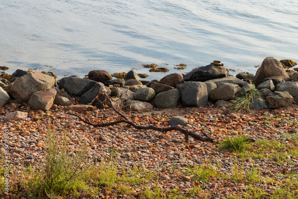 Fototapeta premium Waves coming in to a stone beach on the island of Ven in southern Sweden during a summer sunrise. 