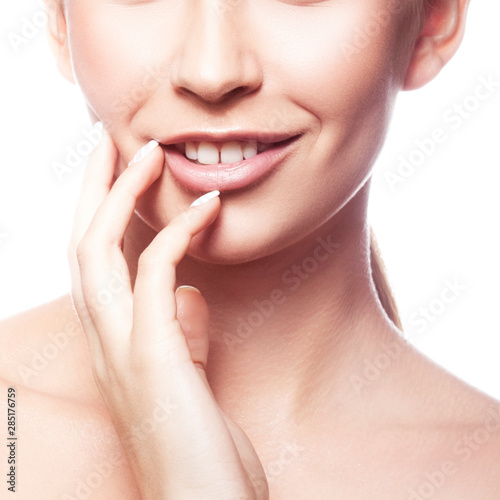 Beauty partial face, model woman applying cream on her face, perfect skin, happy smile, natural nude makeup. Facial treatment concept