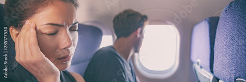 Sick fear of flying inside plane cabin woman in airplane with headache panoramic banner. Asian passenger on travel feeling sick with stress anxiety migraine. Couple tourists. photo