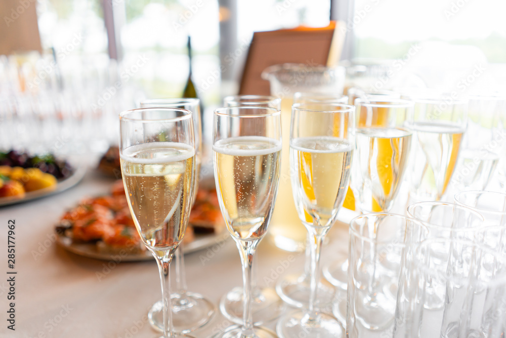 reception. Table top full of glasses of sparkling white wine with canapes and antipasti in the background. champagne bubbles