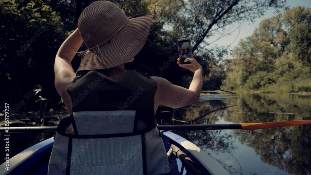 Girl Making Self Photo And Answer To Video Call.Selfie On Mobile Phone In Beautiful Place On Tranquil Water Pond At Sunset Time.Woman Taking Selfie On A Kayak Boat On Evening. Girl Making Self Photo And Answer To Video Call.Selfie On Mobile Phone In Beautiful Place On Tranquil Water Pond At Sunset Time.Woman Taking Selfie On A Kayak Boat On Evening.