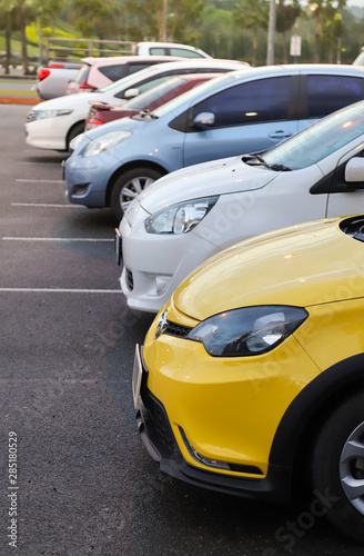 Closeup of front side of yellow car and other cars parking in parking area. Vertical view.