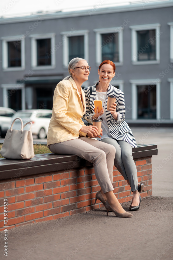 Obraz premium Two modern women sitting on the bench outdoors