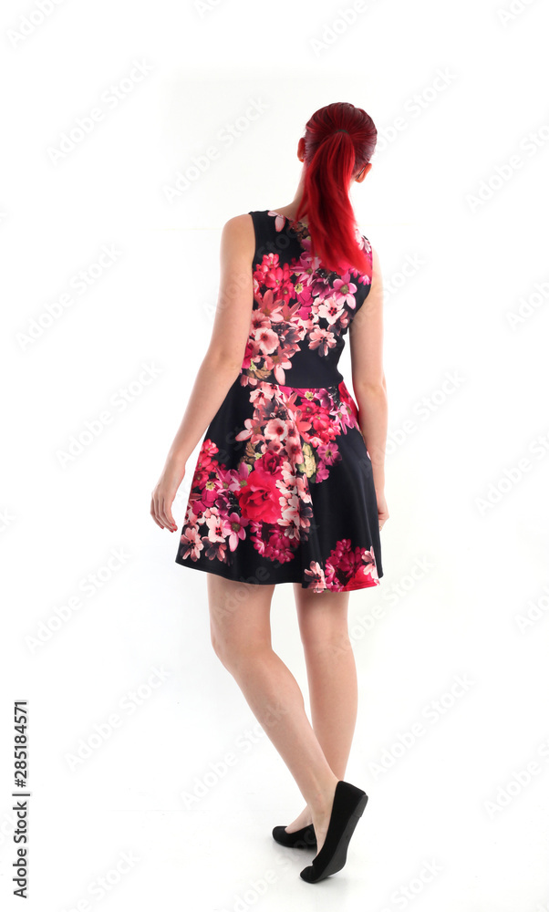 full length portrait of red haired girl wearing a cute flower patterned dress. Standing pose against a white studio background. full length portrait of red haired girl wearing a cute flower patterned dress. Standing pose against a white studio background.