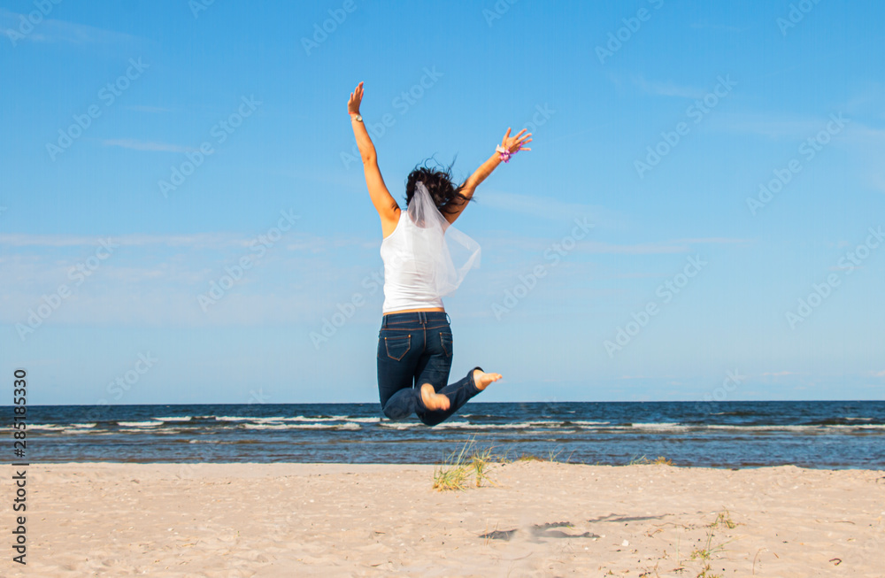 girl in a white blouse jumps to the sky on the shore of the blue sea girl in a white blouse jumps to the sky on the shore of the blue sea