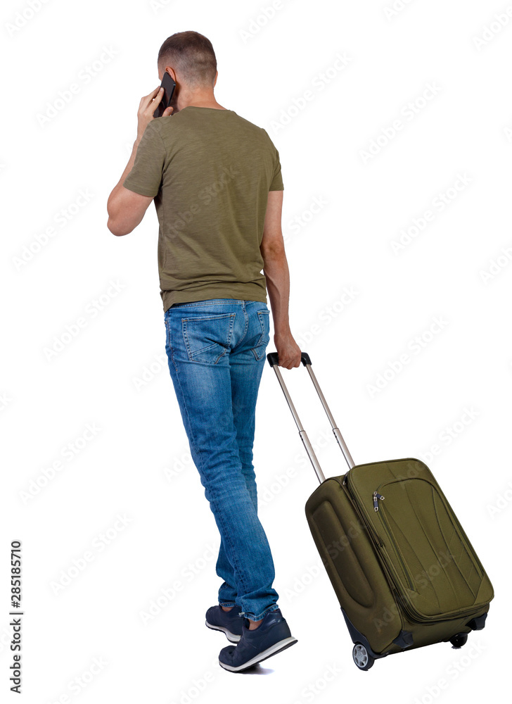 Back view of walking man with suitcase talking on the smartphone. Back view of walking man with suitcase talking on the smartphone.