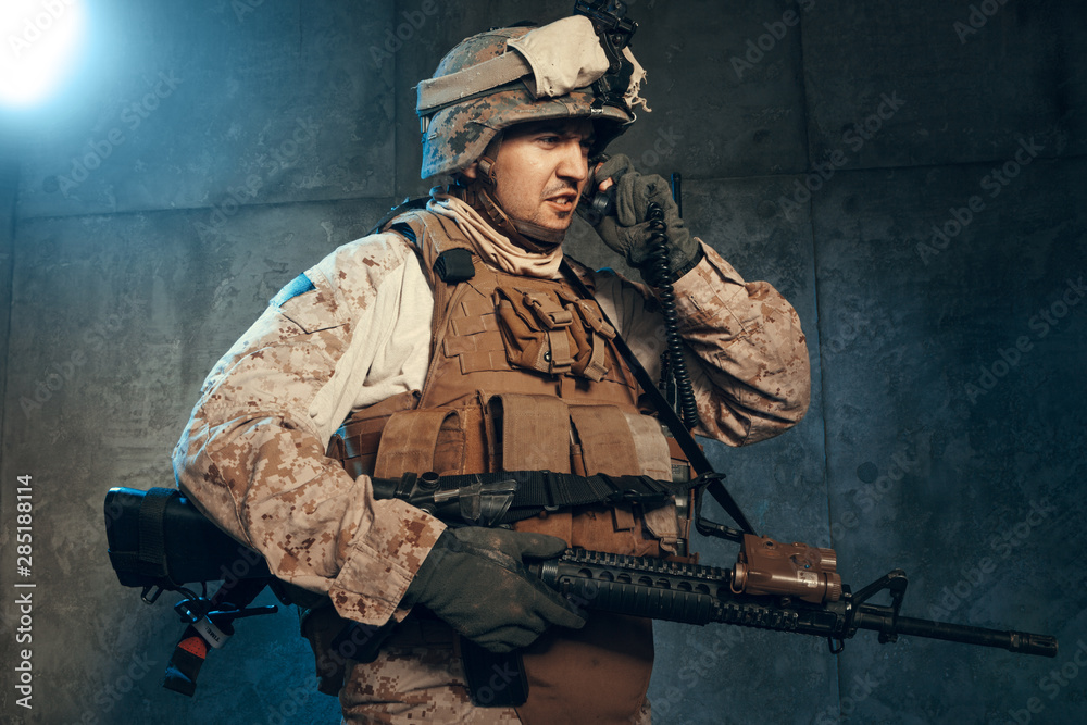 Young man in military outfit a mercenary soldier in modern times on a dark background in studio Young man in military outfit a mercenary soldier in modern times on a dark background in studio