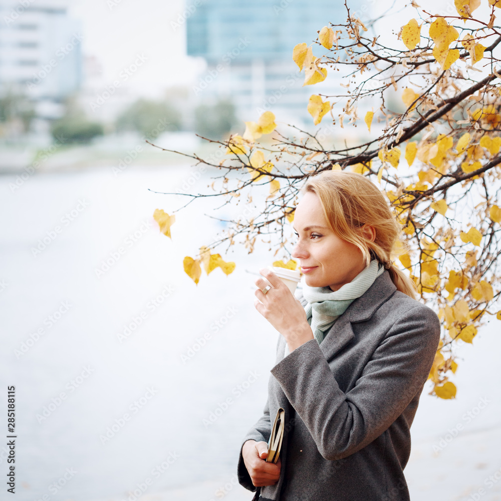 Young woman walking and drinking take away coffee in the city