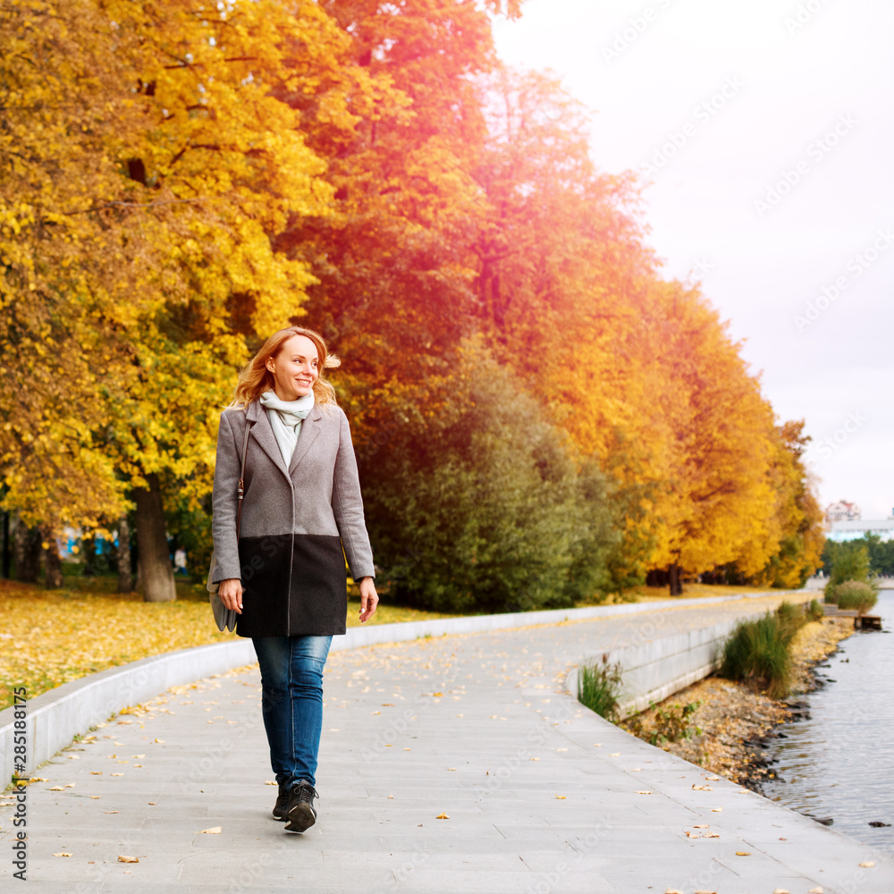 Elegant confident woman walking along the river in city park