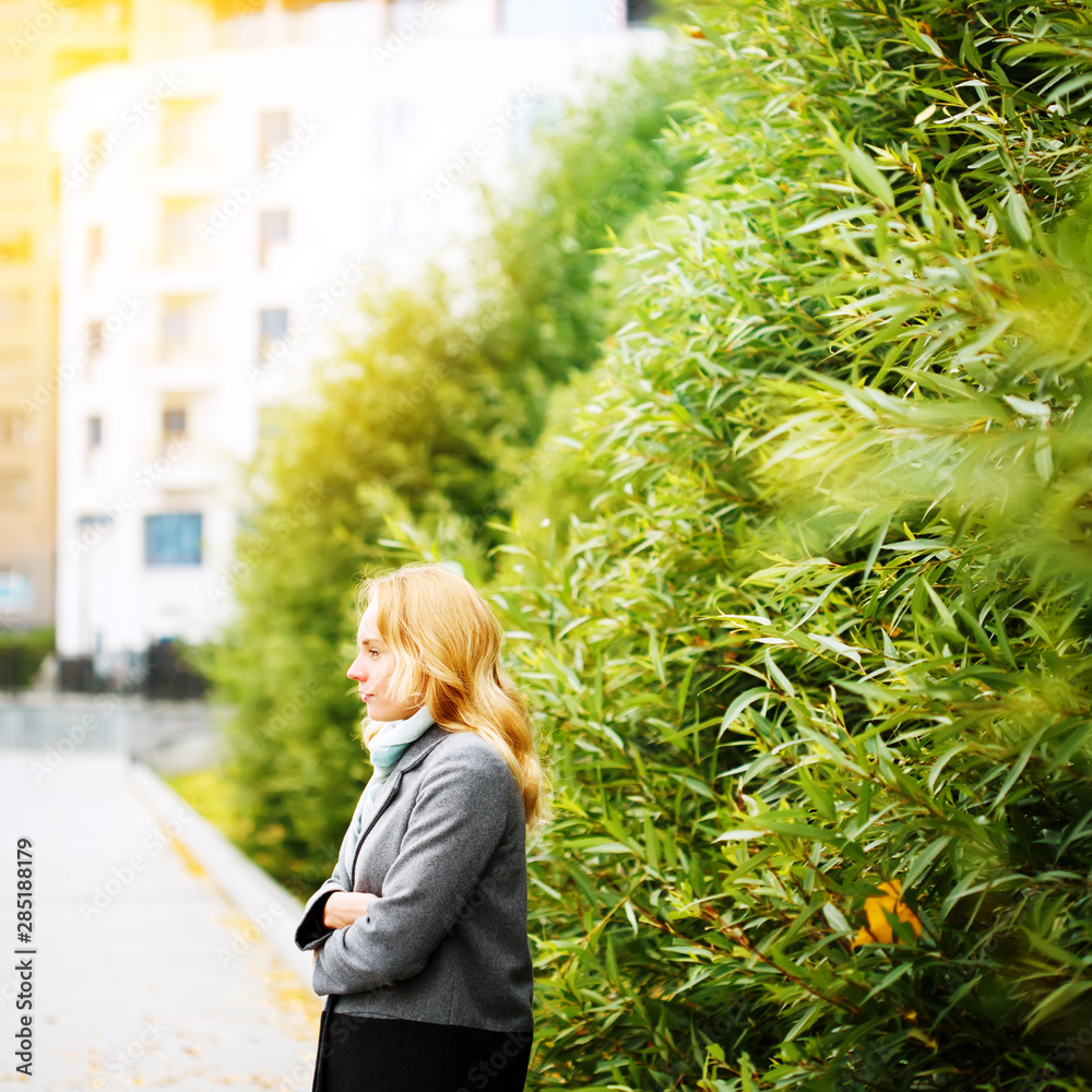 Young thoughtful woman standing alone in the city park