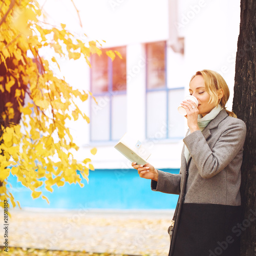 Creative woman in autumn park drinking coffee