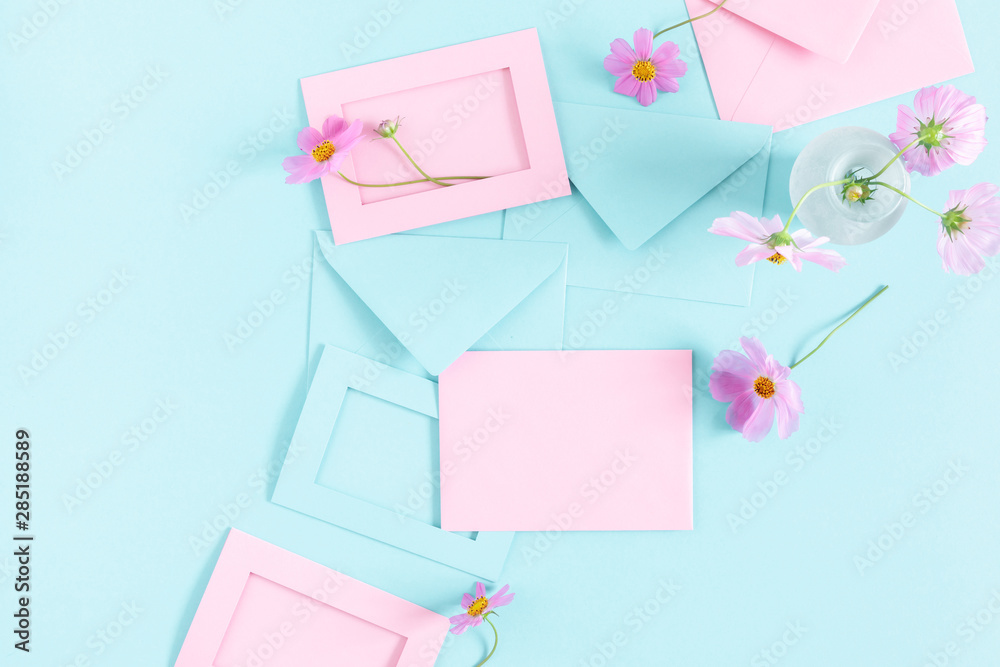 Flowers composition romantic. Pink cosmos flowers, pink and blue envelopes on pastel blue background. Flat lay, top view, copy space