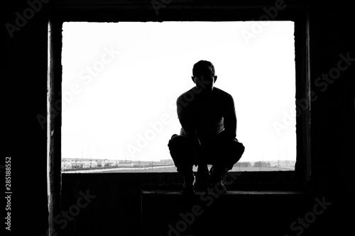 silhouette of man sitting on floor and looking at screen