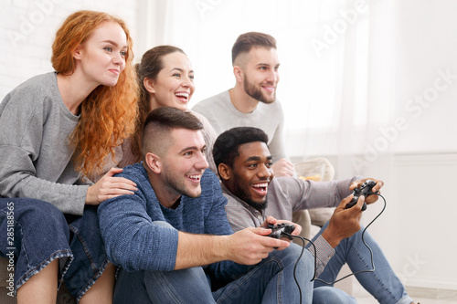Group of friends having fun, playing video games © Prostock-studio