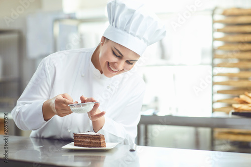 Confectioner decorating chocolate cake in pastry shop. photo