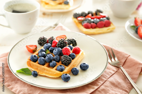 Plate with tasty waffle and berries on table