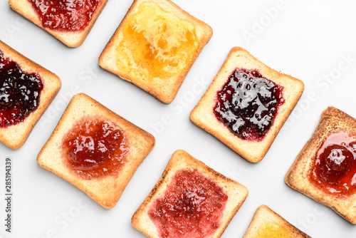 Tasty toasted bread with different jams on white background