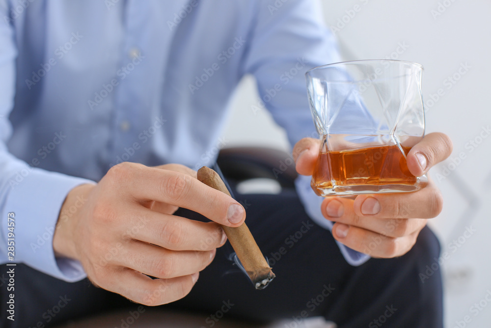Man with glass of whiskey and cigar at home, closeup Man with glass of whiskey and cigar at home, closeup