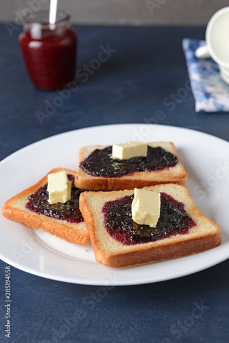 Plate with tasty toasted bread, butter and jam on table