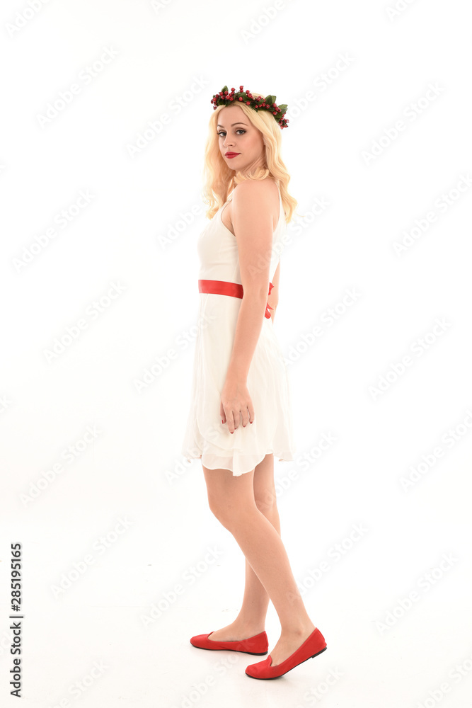 full length portrait of blonde girl wearing a white dress and flower crown. Standing pose, isolated against a white studio background. full length portrait of blonde girl wearing a white dress and flower crown. Standing pose, isolated against a white studio background.