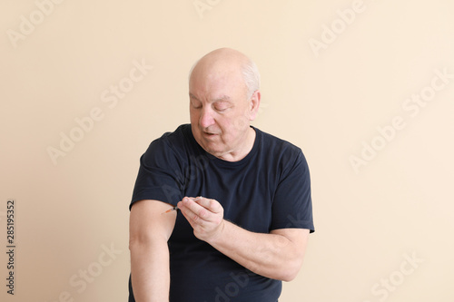 Diabetic man giving himself insulin injection on light background