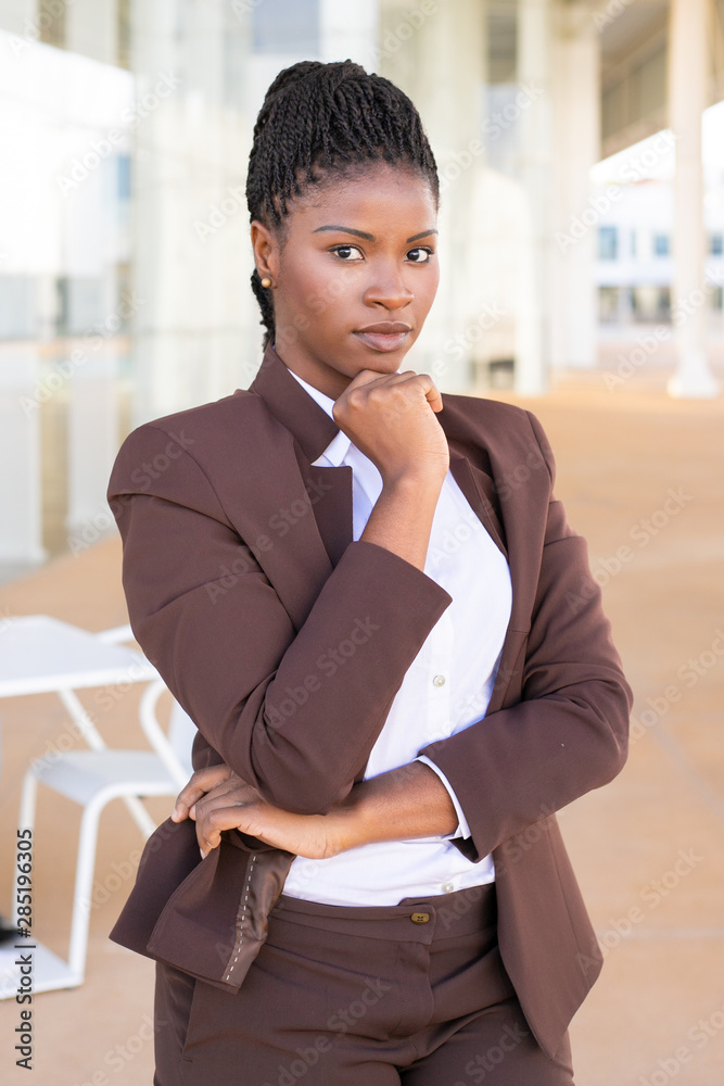 Smiling black business woman pointing on camera in office Stock