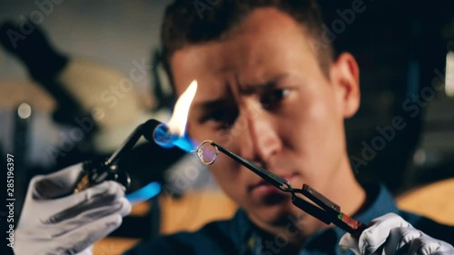 A silversmith is burning a ring with no stones