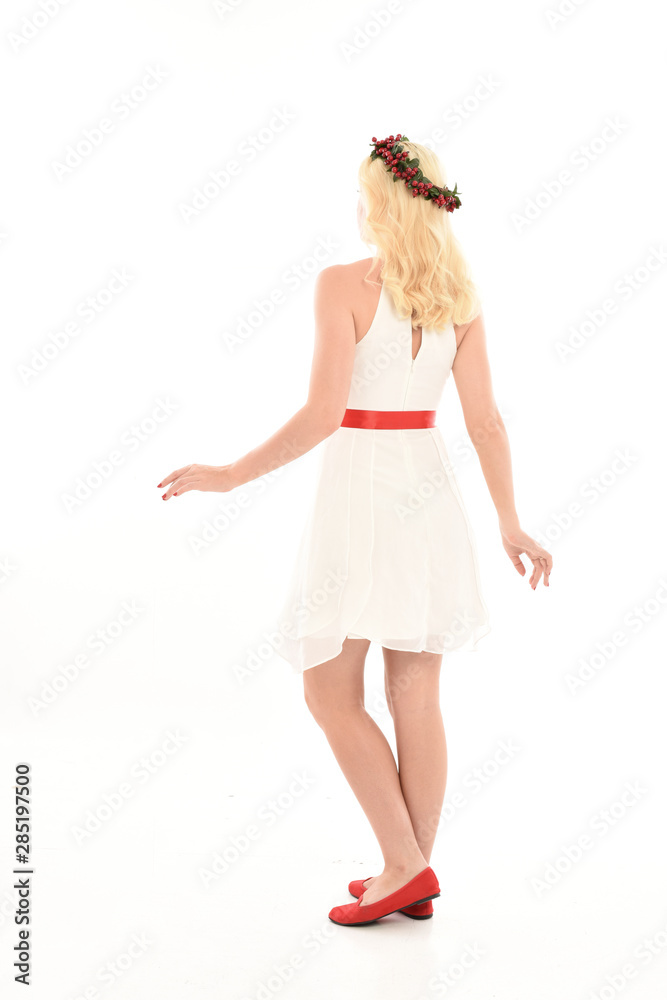 full length portrait of blonde girl wearing a white dress and flower crown.  Standing pose, isolated against a  white studio background.