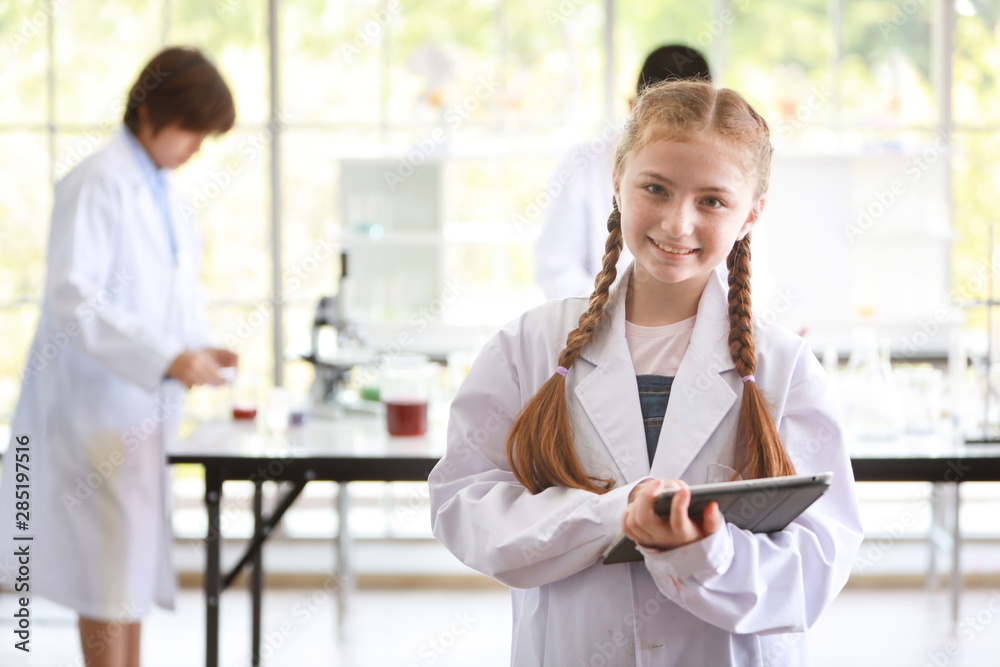 smart kid girl holding tablet whole experimenting science room and looking at camera with happy smiling face smart kid girl holding tablet whole experimenting science room and looking at camera with happy smiling face