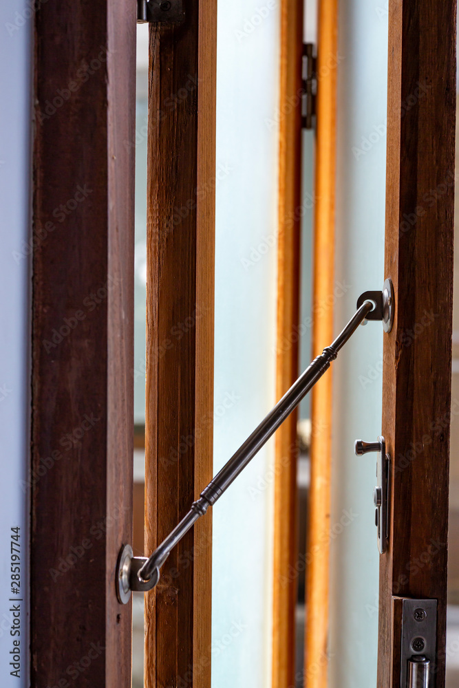 Aluminium Latch  is connected to ajar frosted Glass and wooden door frame, Close up & Macro shot, Selective focus, Home concept