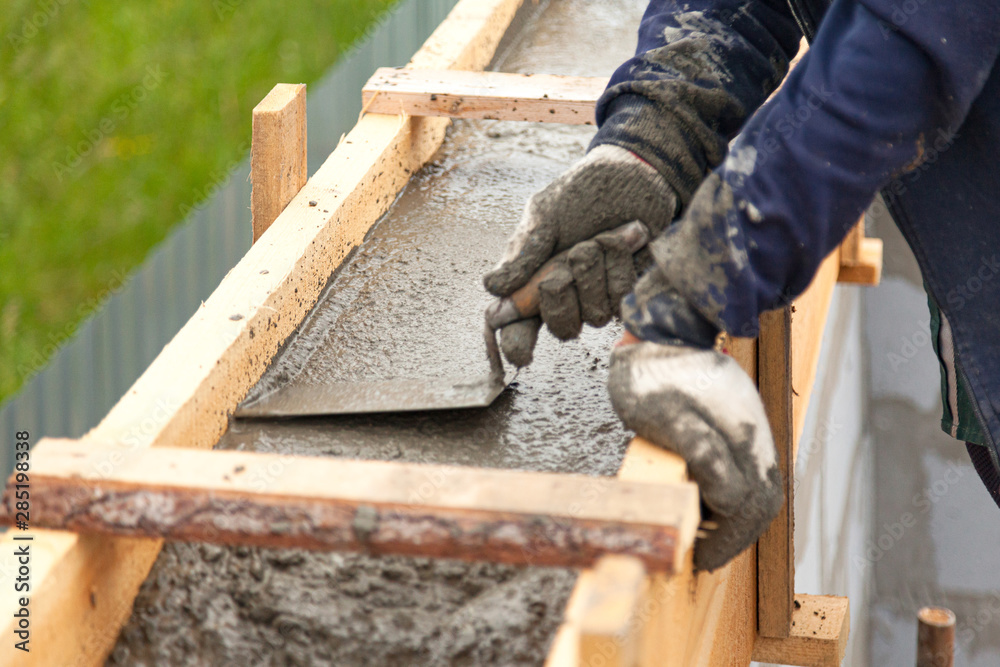 Worker levels concrete in formwork using a trowel